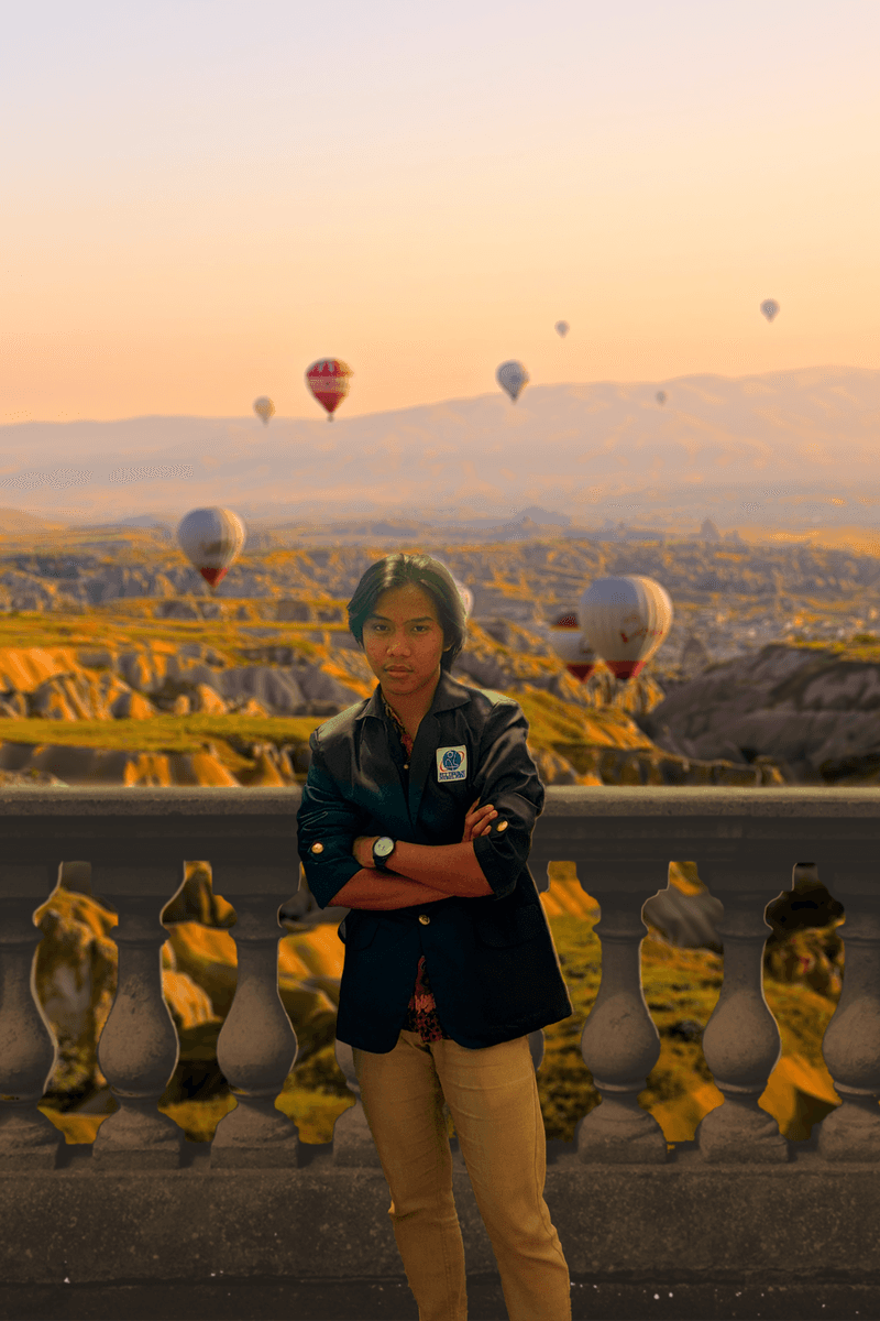 Alfian Nur Usyaid standing before a hot-air-balloon landscape