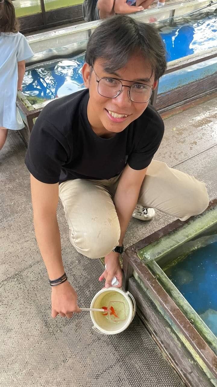 Alfian Nur Usyaid holding a small bucket beside water tanks
